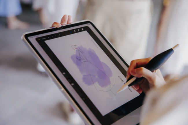 Close-up of a Drawing Booth artist creating a guest fashion sketch on an iPad