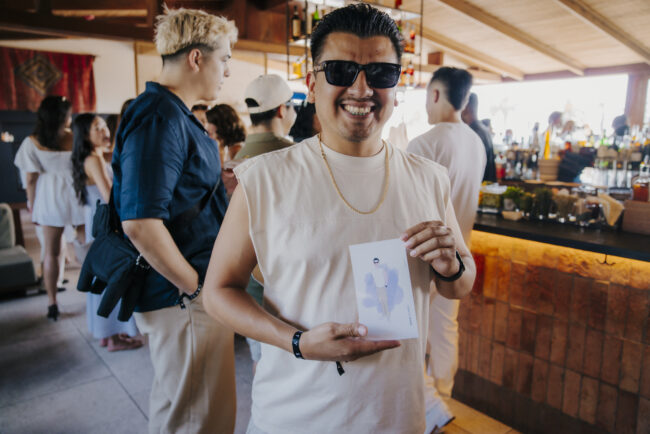 Smiling guest displaying his personalized fashion portrait at the Savage X Fenty summer event